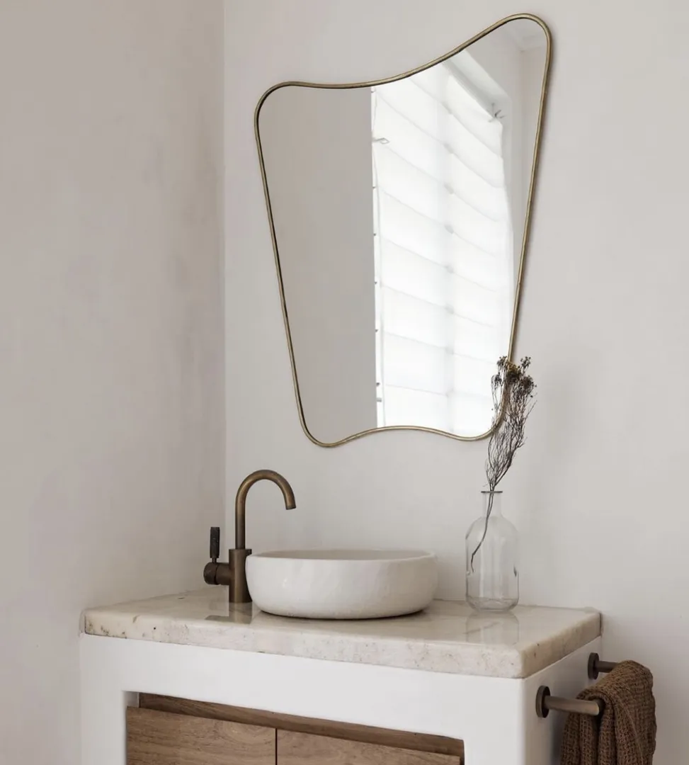 Modern bathroom vanity with round mirror and brown accents.