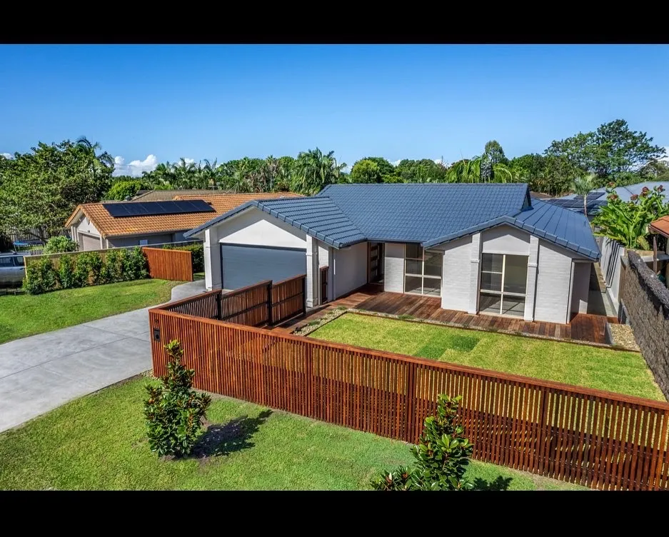 Modern house with blue roof and wooden fence.