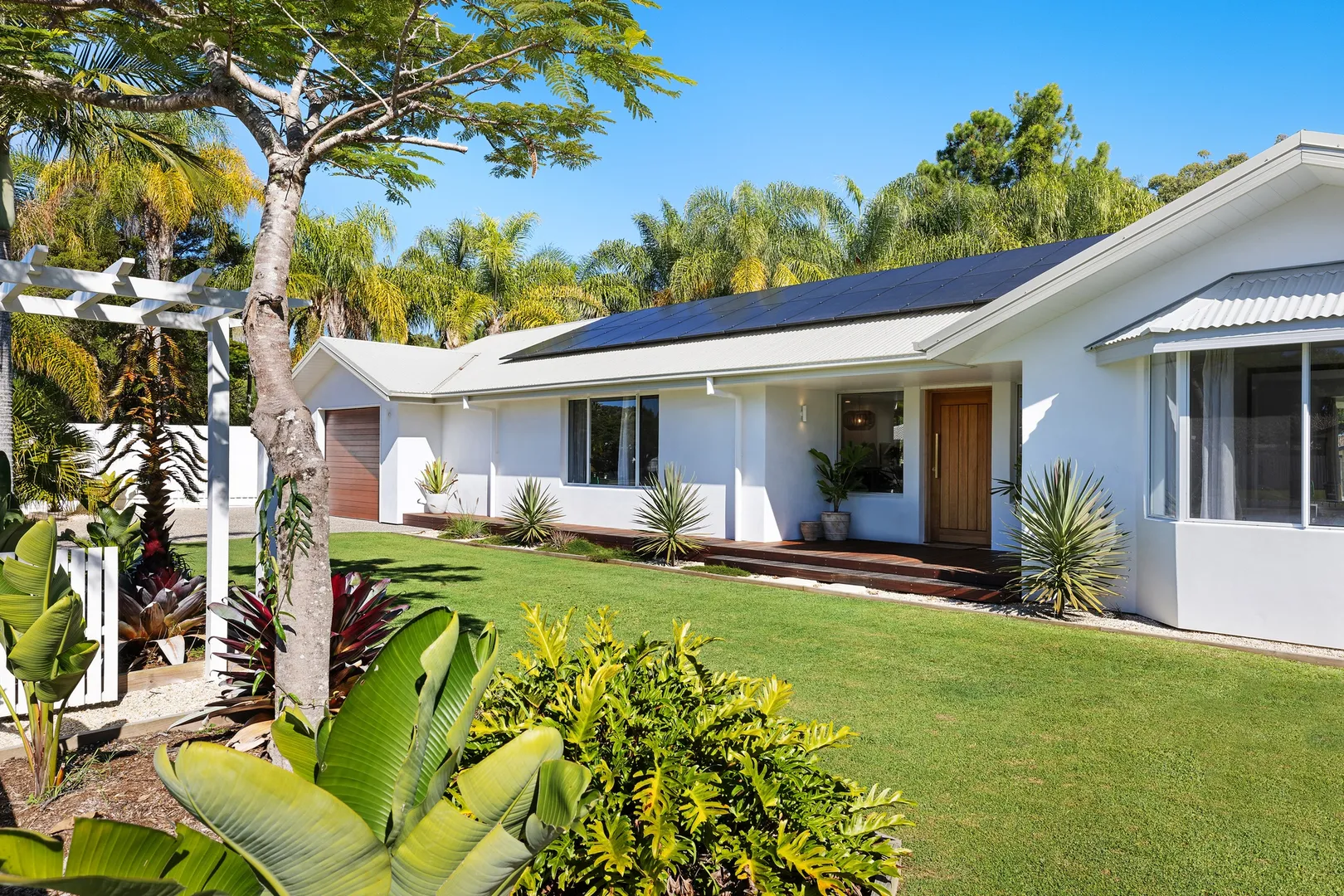 Modern home with solar panels and tropical landscaping.