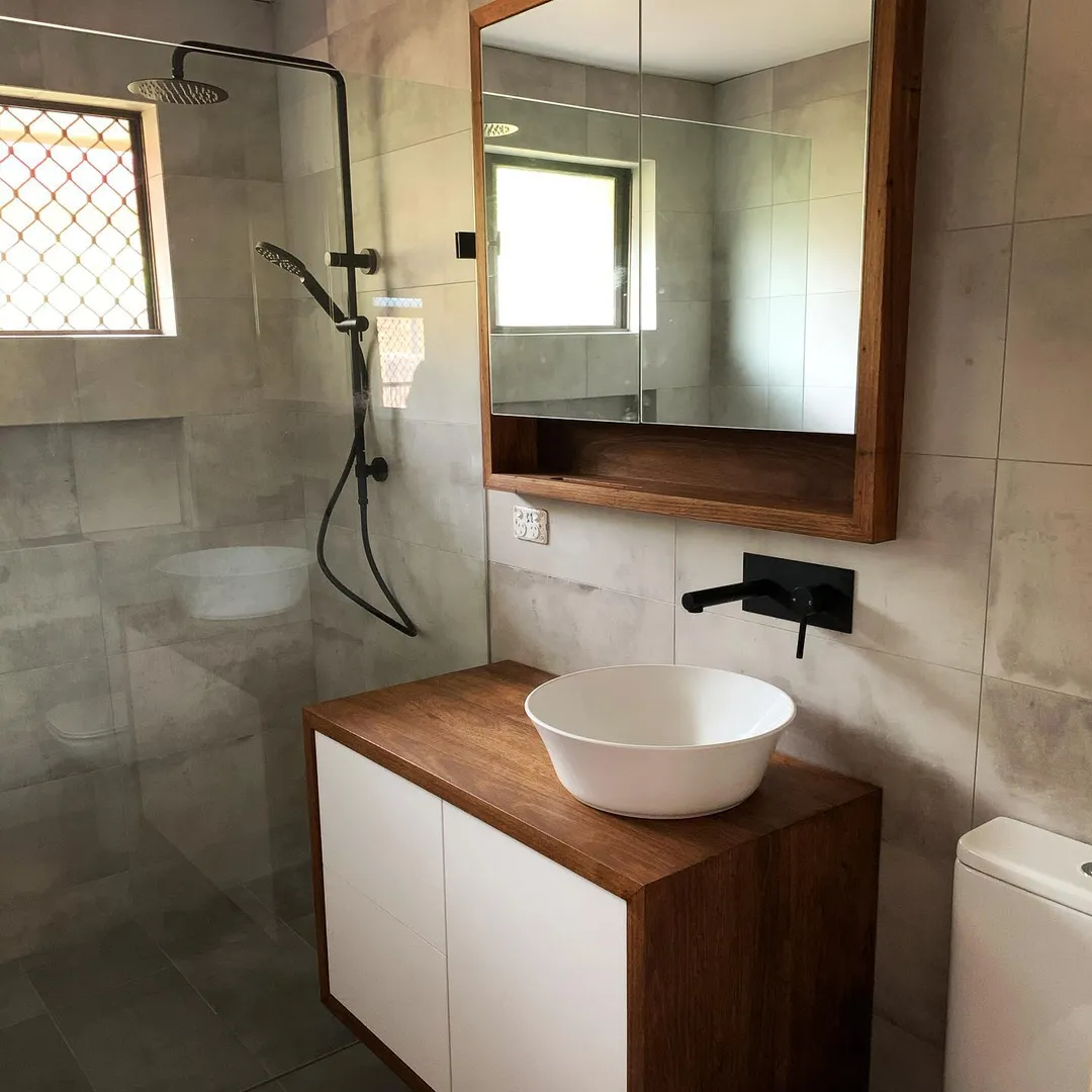 Modern bathroom with wooden vanity, vessel sink, and glass shower.